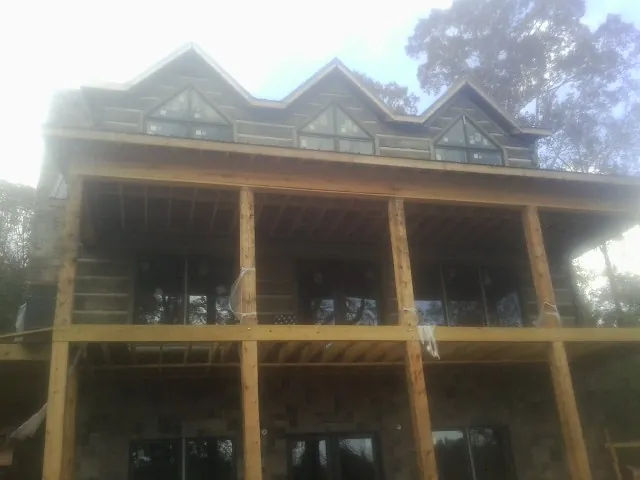 Dormers and porch framing on a large log home under construction — Roof Coating work by our crew in Chelsea
